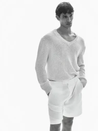 Model Calvin van Capelleveen wearing a textured knit sweater and white shorts against a white backdrop