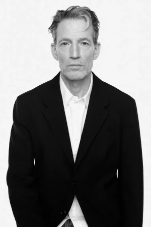 Portrait of a man in a dark blazer and white collared shirt against a white seamless background