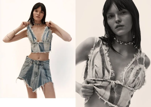 A fair-skinned woman poses indoors, wearing a distressed denim crop top and skirt, complemented by a choker necklace and silver bracelets.