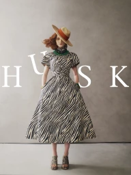 Model wearing a zebra print dress and wide-brim hat against a neutral textured studio background with overlaid HUSK typography