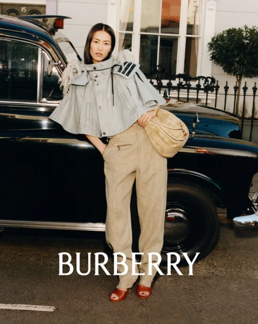 Fashion shot featuring an Asian woman in stylish cape and trousers, next to a black taxi cab, with the brand BURBERRY visible.