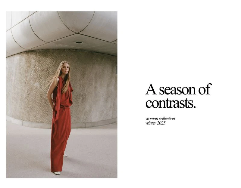 Indoor fashion shot of a blond woman in a red dress. She is standing in front of a light-stone wall in a minimalist, modern building.