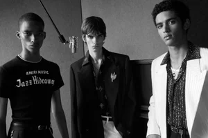Three male models in tailored designer apparel posing inside a recording studio for Amiri