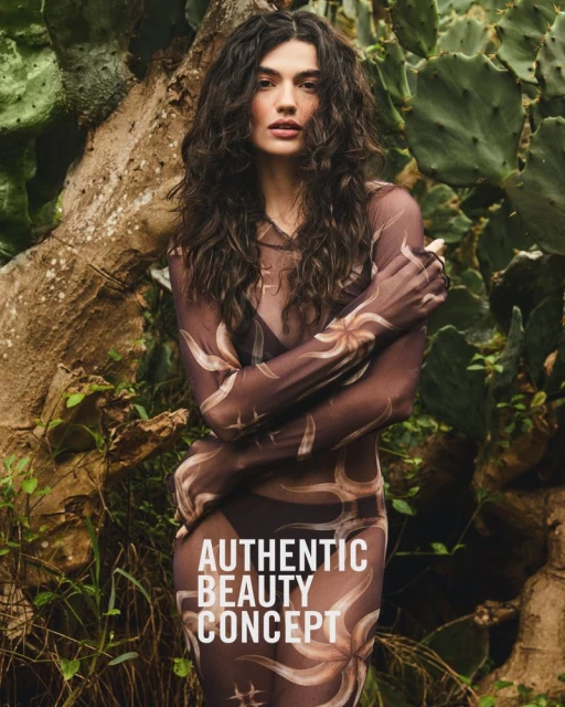 Brunette woman in patterned dress posing by a tree with cactus. Fashion editorial, beauty concept with neutral earth tones, close up shot.