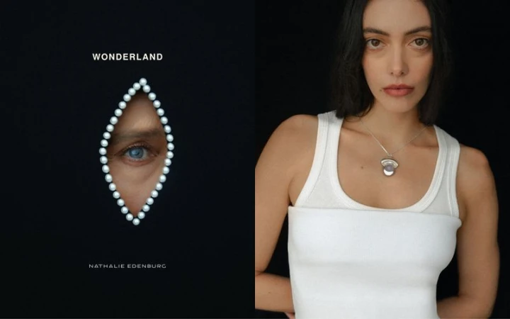 Model wearing white tank top with silver pendant necklace against a black background from Wonderland by Nathalie Edenburg
