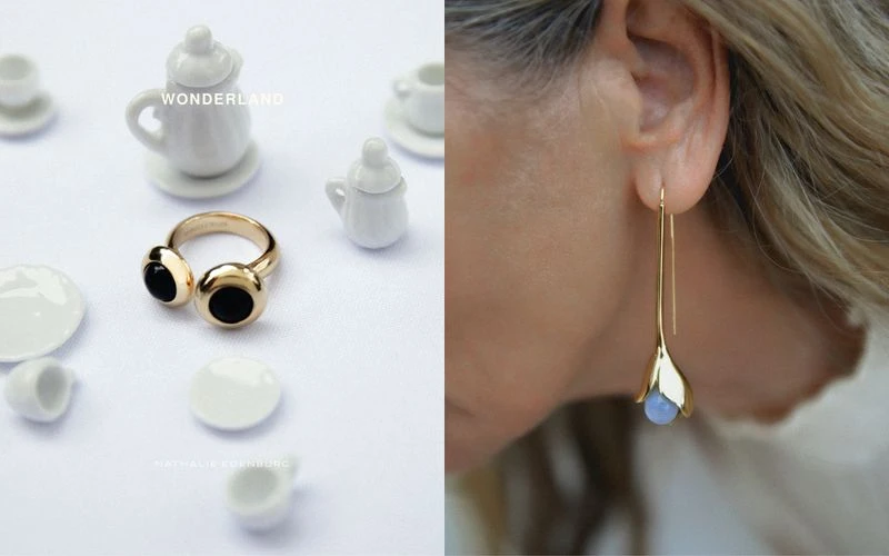 Close-up of an adult female wearing a gold earring, alongside a gold ring and miniature white teacups and plates on a white surface.