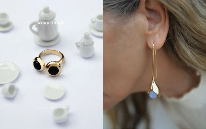 Close-up of an adult female wearing a gold earring, alongside a gold ring and miniature white teacups and plates on a white surface.