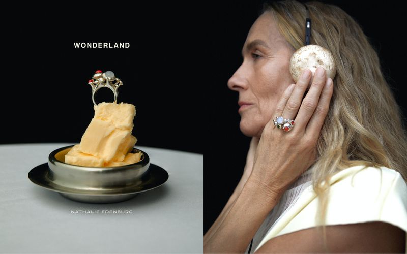 Older adult female wearing headphones and rings poses beside a stack of butter topped with a ring in a studio setting.