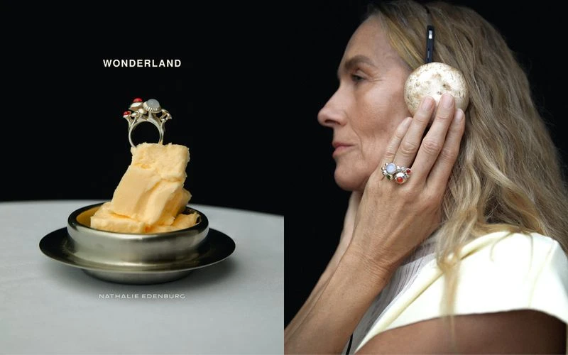 Older adult female wearing headphones and rings poses beside a stack of butter topped with a ring in a studio setting.