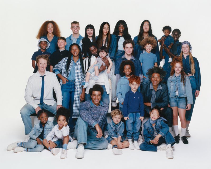 Denim-clad group portrait: large diverse group of adults and children in an indoor setting with denim and blue clothing, posing together.