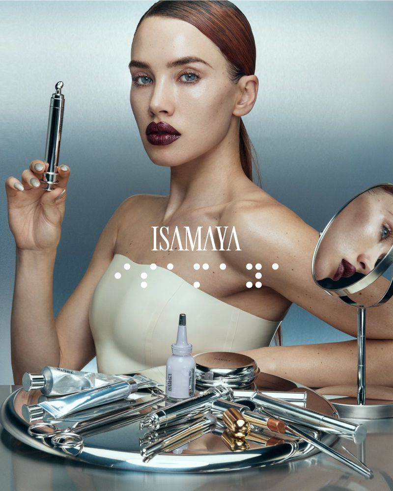 Glamorous beauty shot featuring a woman with sleek hair and dark lipstick, holding a cosmetic tool, with makeup products on a reflective surface.