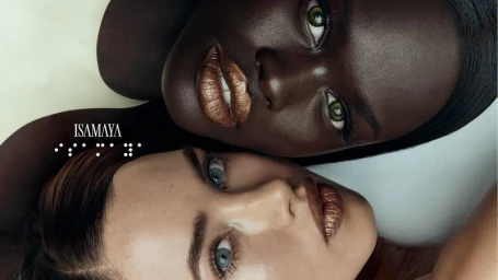 Close-up beauty portrait of two models with metallic bronze lipstick and defined features against a neutral background.