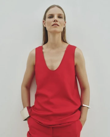 Model Suvi Riggs wearing a red top and trousers with silver cuffs against a plain white wall