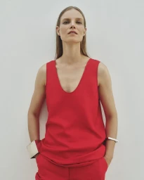 Model Suvi Riggs wearing a red top and trousers with silver cuffs against a plain white wall