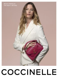 Behati Prinsloo in a white blazer holding a pink leather handbag against a solid pink backdrop for Coccinelle