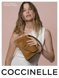 Behati Prinsloo holding a brown leather shoulder bag wearing a white dress against a solid pink backdrop for Coccinelle