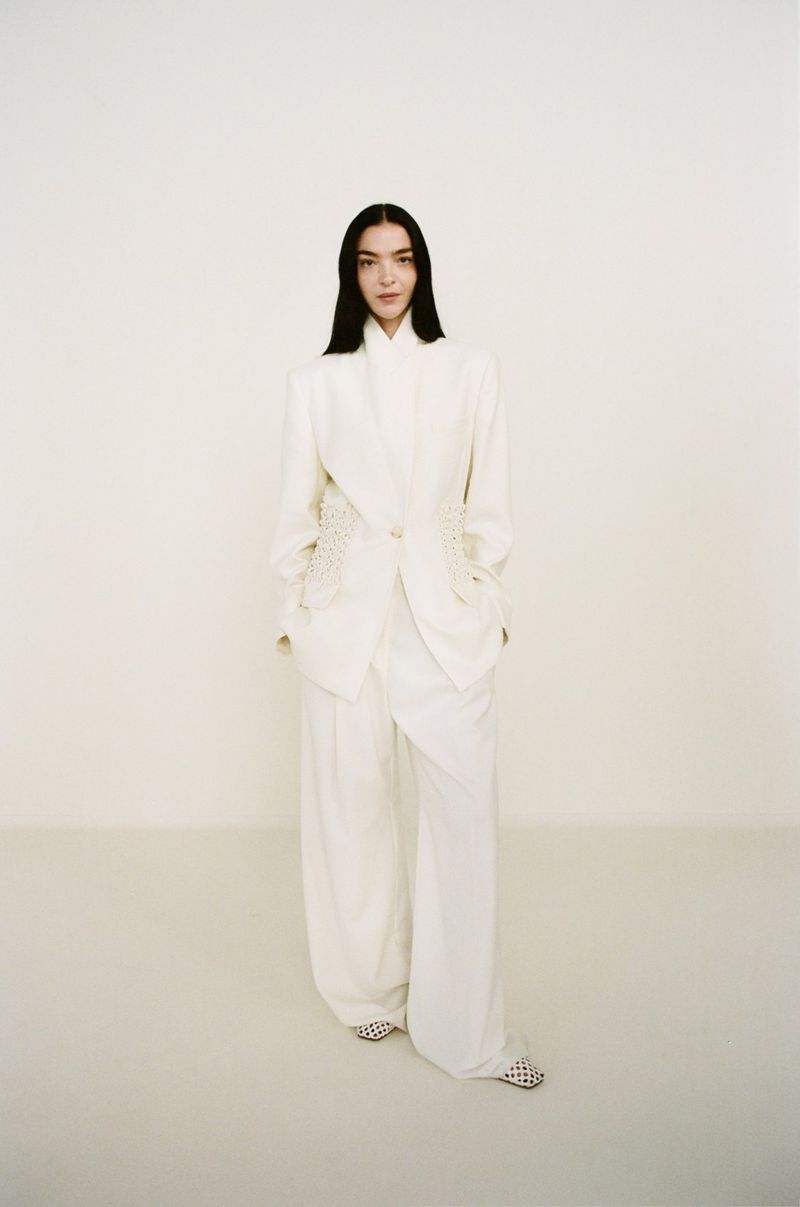 Elegant woman in white blazer and pants. Fashion editorial image with a clean backdrop for beauty, style, and sophisticated apparel.