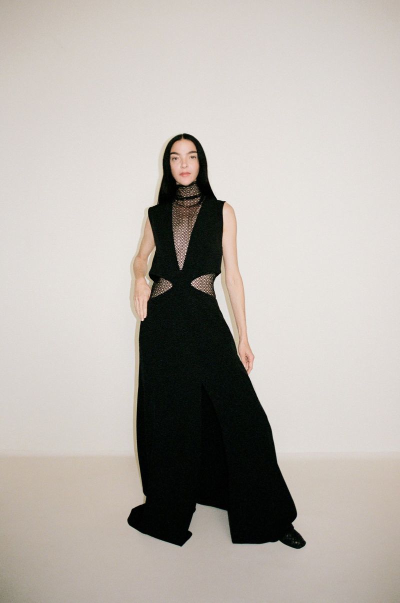 Mariacarla Boscono wearing a black cut-out dress against a plain neutral background for Camilla and Marc