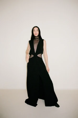 Mariacarla Boscono wearing a black cut-out dress against a plain neutral background for Camilla and Marc