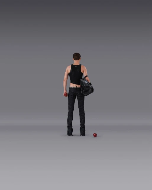 Male figure in black tank top and jeans holds a red apple and black duffel bag against a neutral gray background in a studio setting.