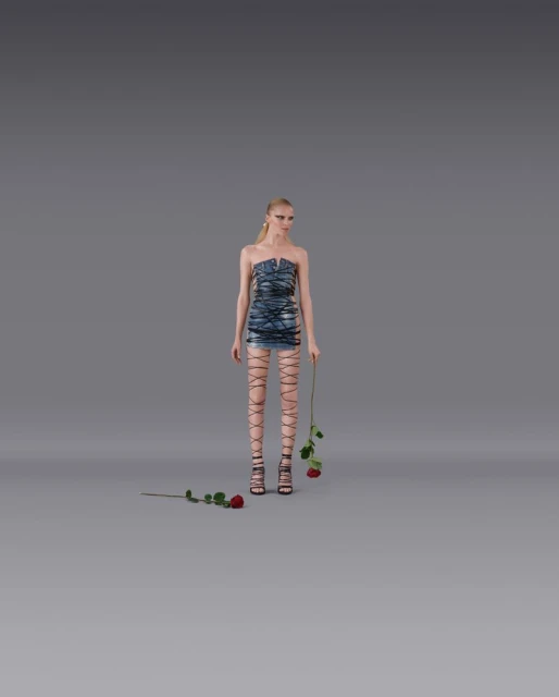 A blonde fashion model in a blue strapless mini-dress and lace-up high heels poses in a studio holding red roses in a full shot.