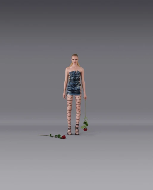 Fashion model in a blue dress and strappy heels poses in a studio setting with roses, against a neutral gray backdrop, medium full shot.