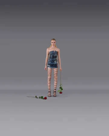 Fashion model in a blue dress and strappy heels poses in a studio setting with roses, against a neutral gray backdrop, medium full shot.