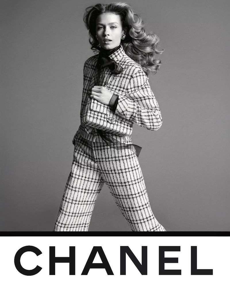 Model in plaid tweed suit and matching bag against grey backdrop for Chanel S/S 25 campaign photographed by Inez and Vinoodh