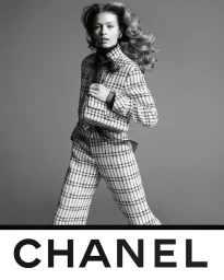 Model in plaid tweed suit and matching bag against grey backdrop for Chanel S/S 25 campaign photographed by Inez and Vinoodh