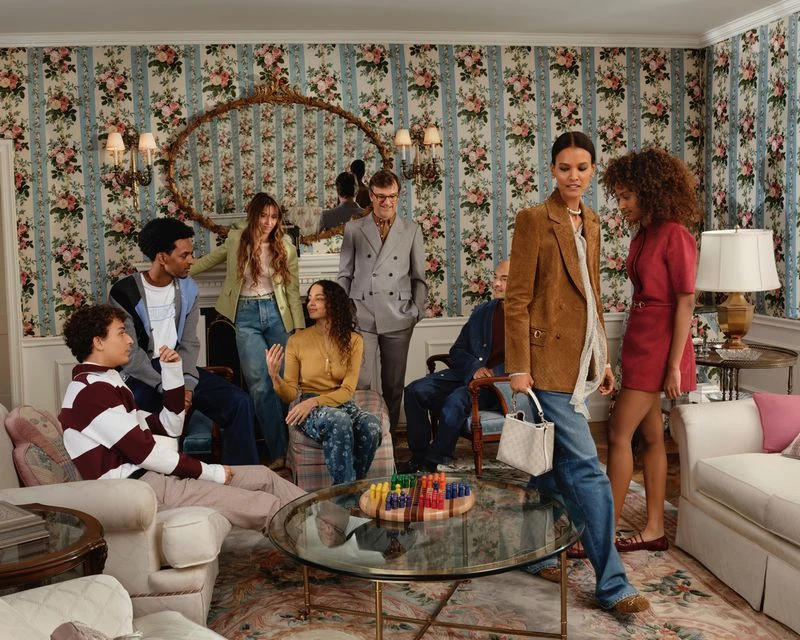 Group of diverse adults and young adults are indoors in a living room with floral wallpaper and playing a board game.