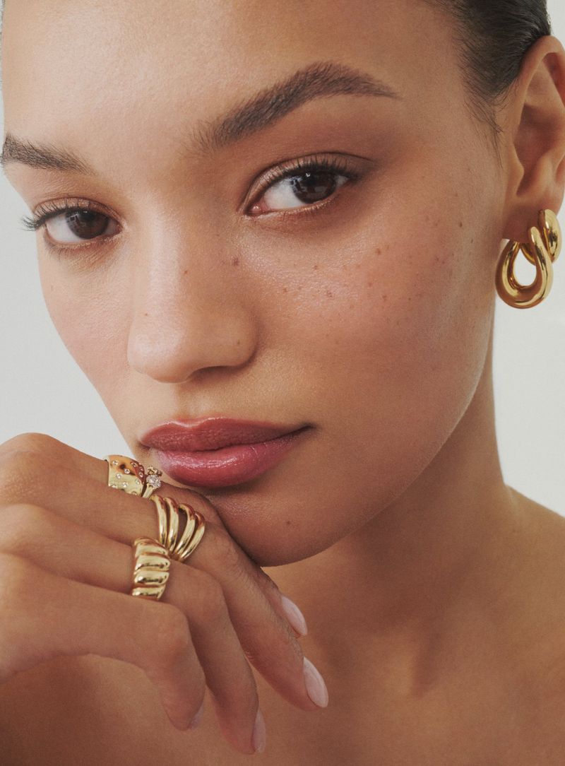 Close-up portrait of model Lameka Fox wearing gold hoop earrings and multiple gold rings for Bloomingdale's Fine Jewelry project