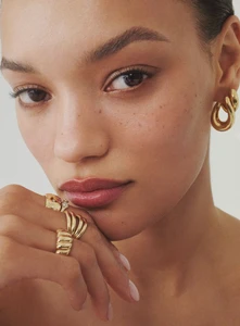 Close-up portrait of model Lameka Fox wearing gold hoop earrings and multiple gold rings for Bloomingdale's Fine Jewelry project