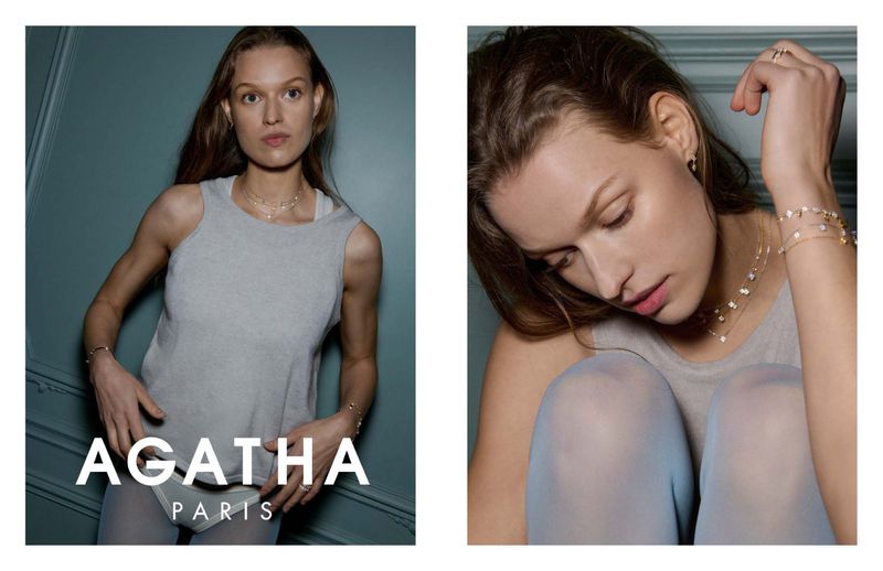 A woman models jewelry in a studio shot, wearing a grey tank top and matching tights, showcasing a necklace, bracelet, and ring.