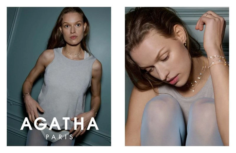A woman models jewelry in a studio shot, wearing a grey tank top and matching tights, showcasing a necklace, bracelet, and ring.