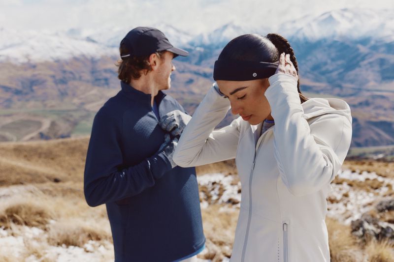 Activewear promo featuring a couple wearing athletic apparel against a snowy mountain backdrop, showcasing outdoor lifestyle and fitness gear.