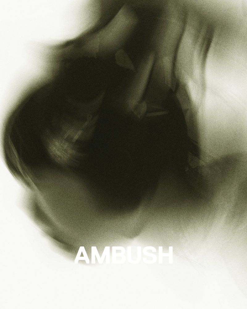 Abstract motion blur of green and white creates a smoky effect.  The word AMBUSH is visible in white lettering at the bottom.