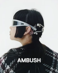 Model in profile wearing futuristic sunglasses and jewelled hair accessories with patterned top for Ambush S/S 25
