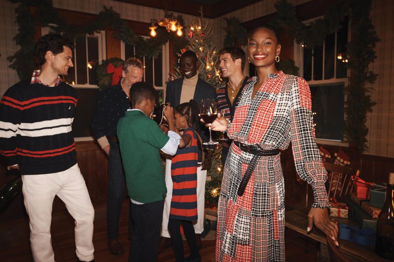 A diverse group gathers indoors for the holidays, featuring adults and children around a Christmas tree with warm lighting.