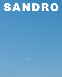 Clear blue sky with large white brand text at the top and a small crescent moon visible below for Sandro S/S 25