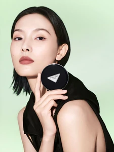 Model Jiali Zhao holding a Prada Beauty mesh cushion compact against a soft green background.