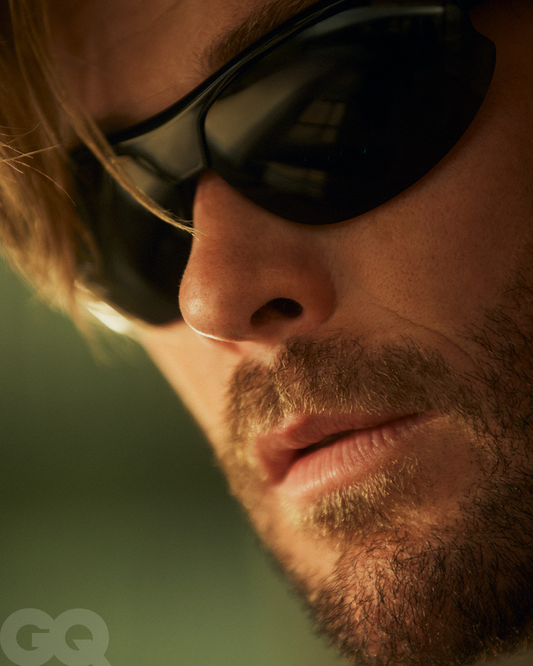 Extreme close up portrait of Chris Hemsworth wearing dark sunglasses and stubble for British GQ portrait