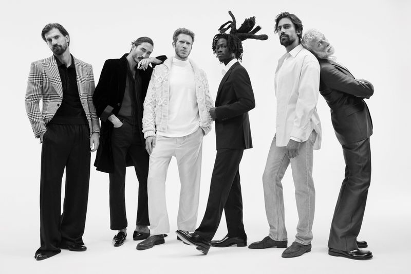 Black and white studio shot of six adult male fashion models in suits, blazers, dress pants, and dress shoes, posed against a white backdrop.
