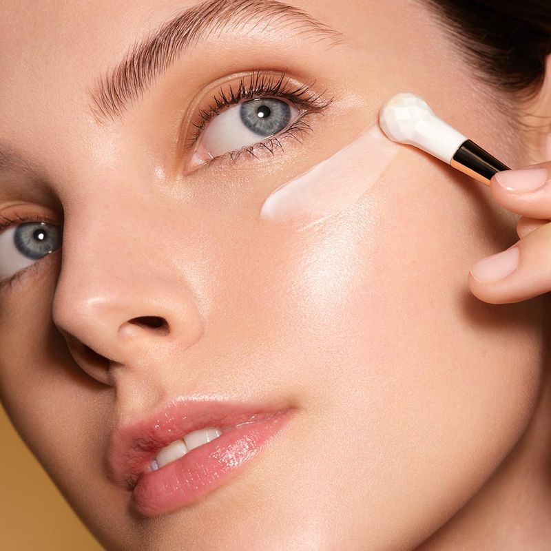 Close-up of a woman's face as makeup is applied with a brush, showcasing beauty and cosmetic techniques for skin enhancement.