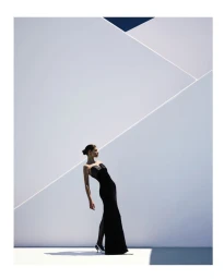 Model Anthi Fakidari in a black strapless gown posing against a minimalist white architectural wall for Roland Mouret Pre Fall