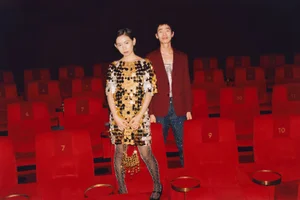 Two models standing inside a dimly lit cinema with rows of red velvet seats for Selfridges Lunar New Year campaign