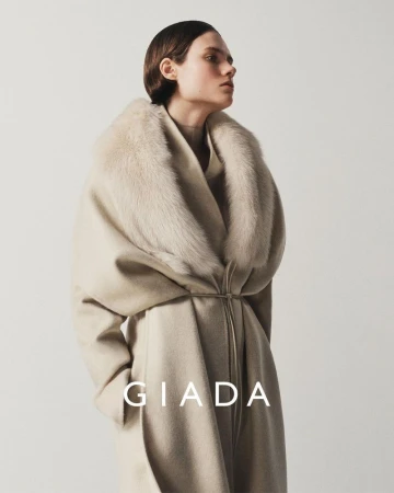 Model wearing a beige wool coat with a fur collar against a light background for Giada