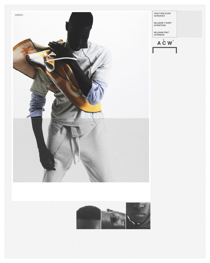 Dark-skinned adult male poses indoors wearing gray sweat suit and carrying a mustard-yellow textile accessory over his shoulder.