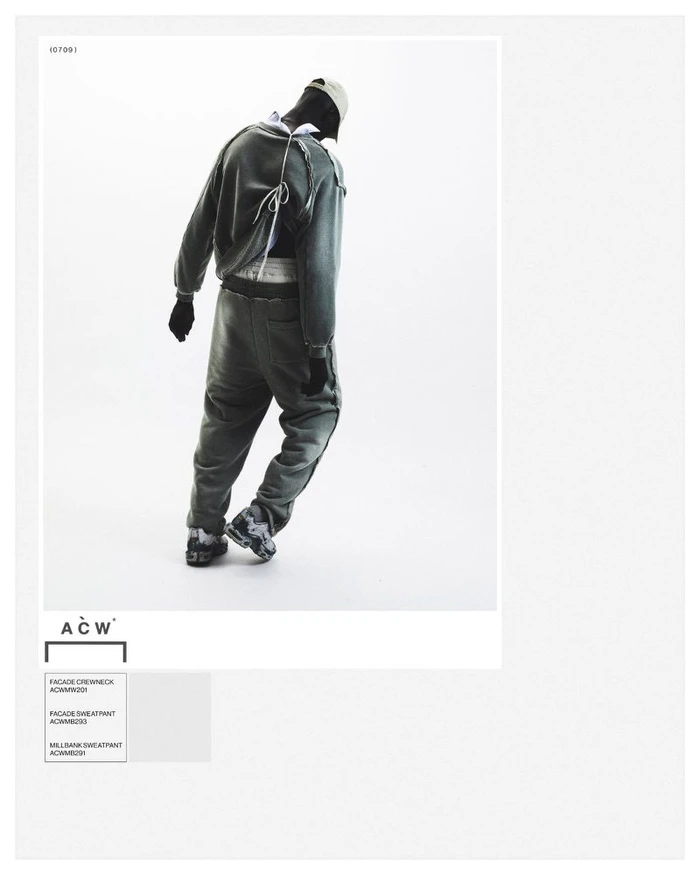 Model from behind wearing grey crewneck sweatshirt and matching sweatpants against a white studio background