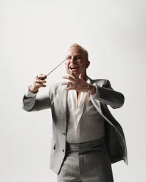 A man in a grey suit holding a baton against a plain white background