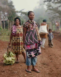 Two indigenous women standing on a dirt path with one holding green bananas, photographed by Hannah Scott-stevenson for Among Equals.